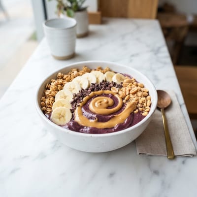 Peanut butter acai bowl topped with banana, cacao nibs and crushed peanuts