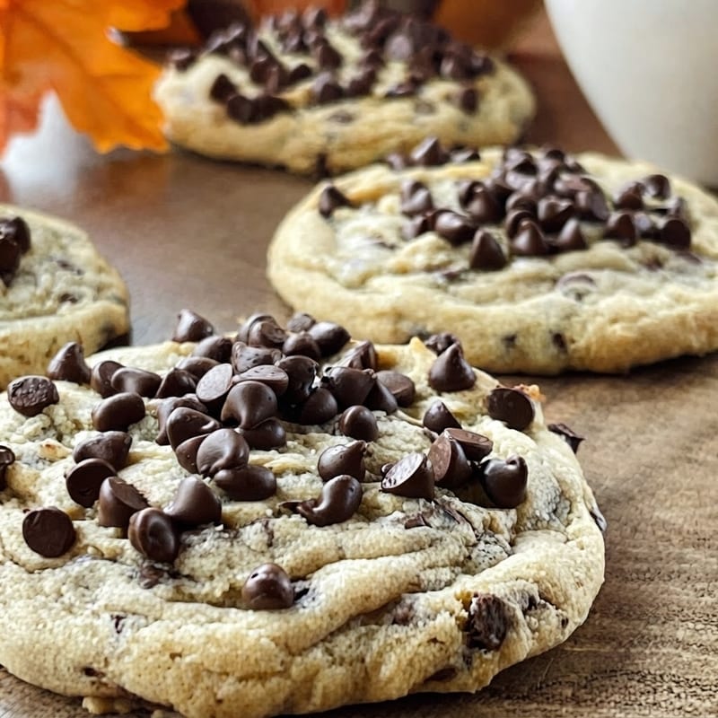 Close-up of thick chocolate chip cookies with glossy chocolate chips on a rustic wooden table